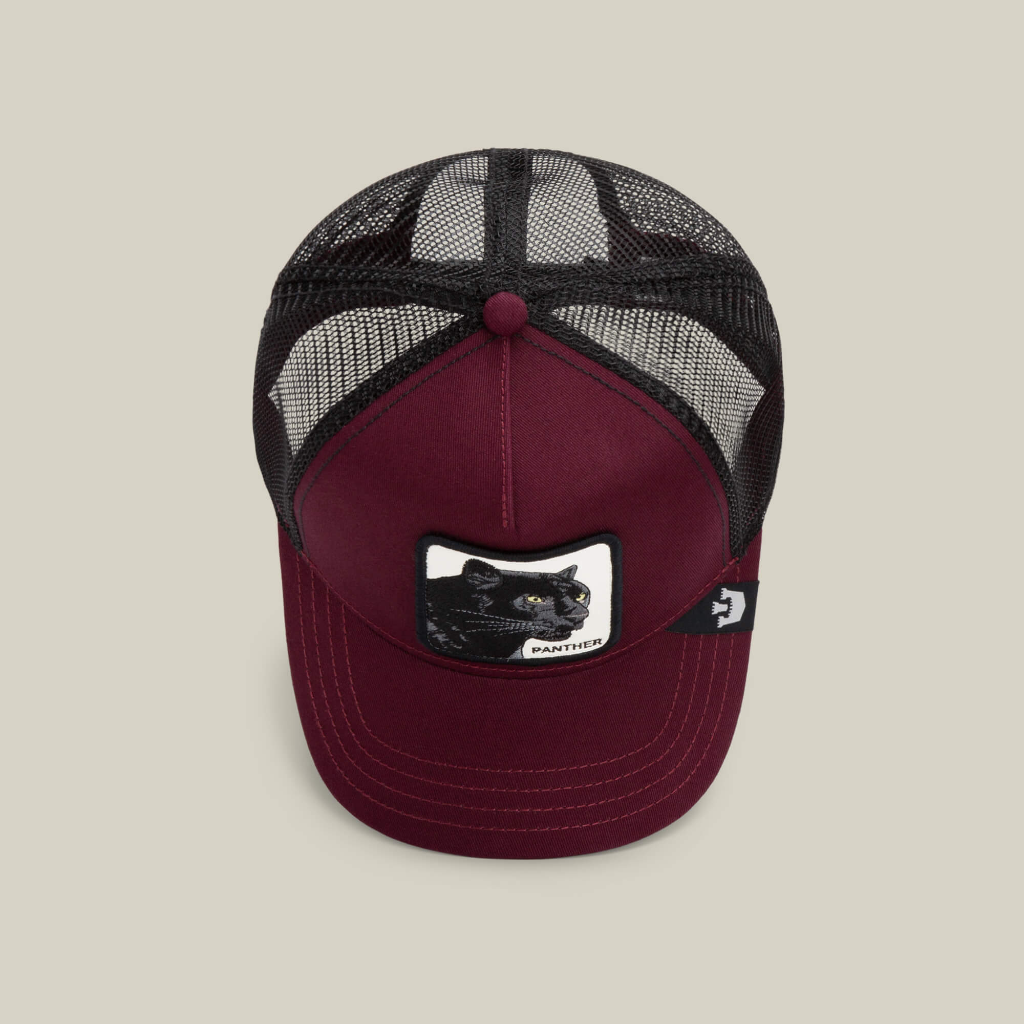 The Panther by Goorin Bros. is a burgundy trucker baseball hat with a black mesh back and a front patch featuring an embroidered black panther.