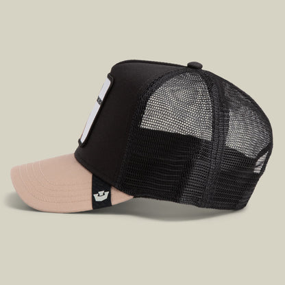 The Bad Boy by Goorin Bros is a black and beige mesh trucker hat with a two-tone design, featuring a black mesh back and black fabric front panel with a light pink brim, displayed on a neutral studio background.