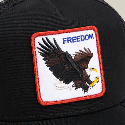 The Farm's "The Freedom Eagle" is a black cap with a patch showing an embroidered flying bald eagle and the word FREEDOM in blue, symbolizing pride while standing out from the ordinary.