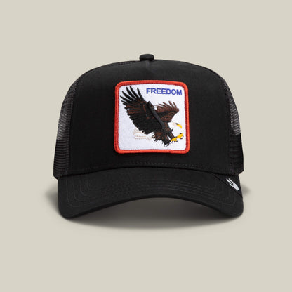 The Freedom Eagle by The Farm is a black mesh trucker hat featuring a front patch with an eagle in flight and the word "FREEDOM" in blue—a bold reminder to soar at a safe distance.