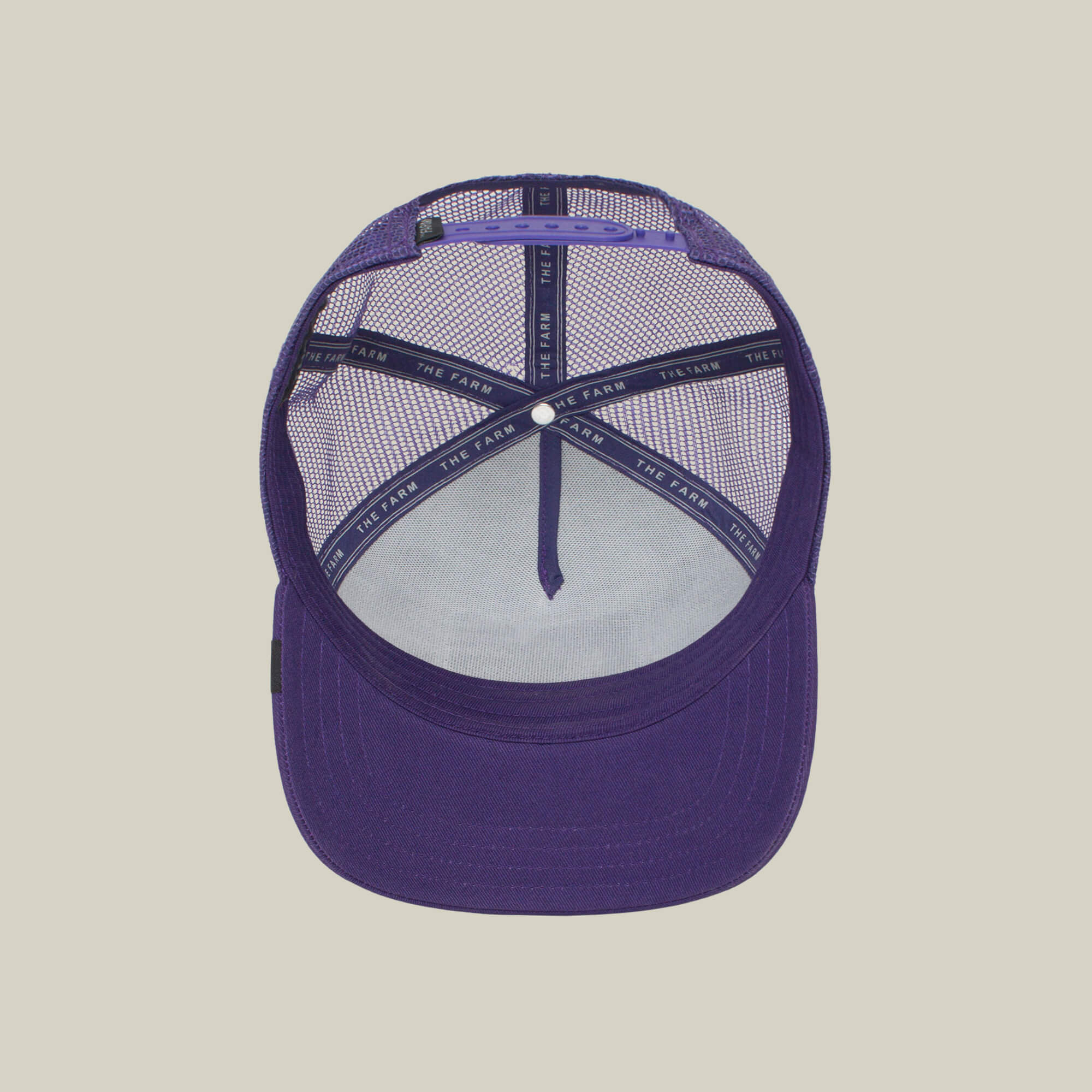 The Lone Wolf by The Farm is a purple mesh trucker hat with an adjustable strap and interior branded taping reading THE FARM, shown from above—ideal for the independent spirit.