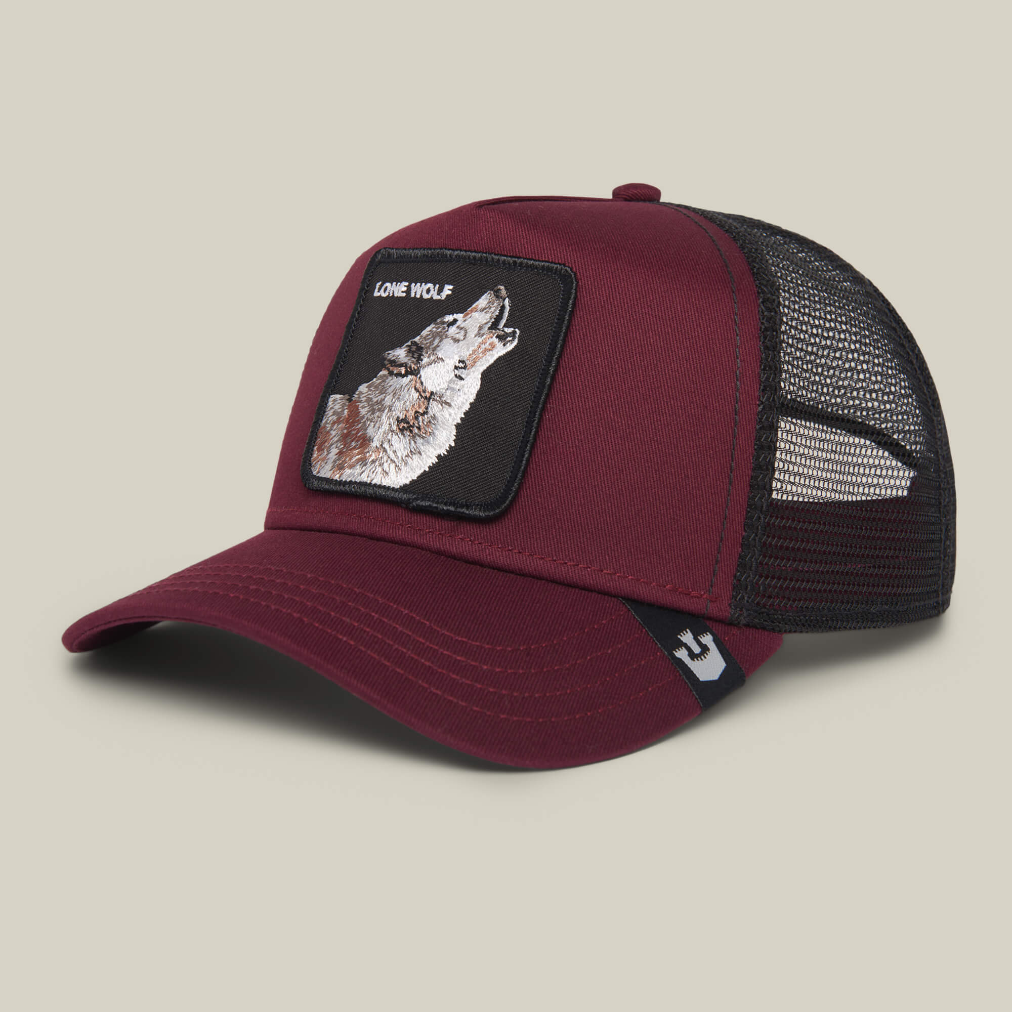 The Farm’s The Lone Wolf cap is a maroon and black mesh trucker hat featuring a front patch with a wolf and "LONE WOLF" text—ideal for the independent spirit, shown against a plain background.