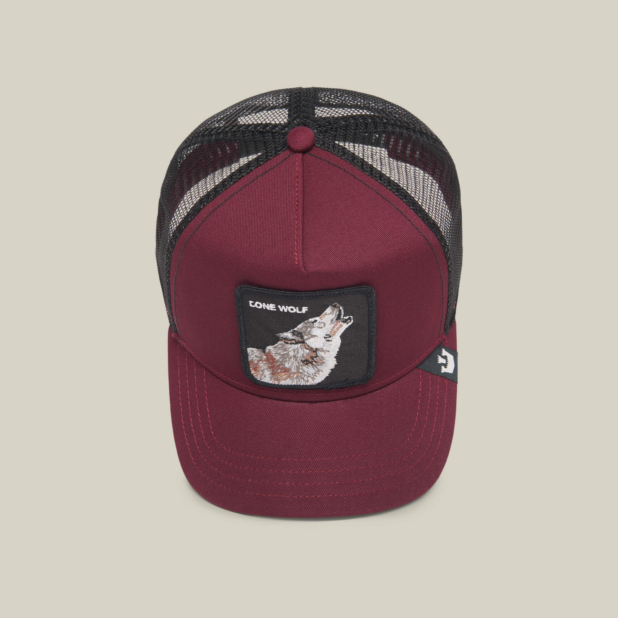 The Farm’s "The Lone Wolf" is a maroon trucker hat with a black mesh back and a front patch of a howling wolf and "LONE WOLF"—ideal for independent spirits.