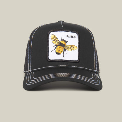 The Queen Bee by The Farm: A black trucker hat with white stitching, accented by a yellow bee patch and “QUEEN”—a stylish crown for those ready to slay.