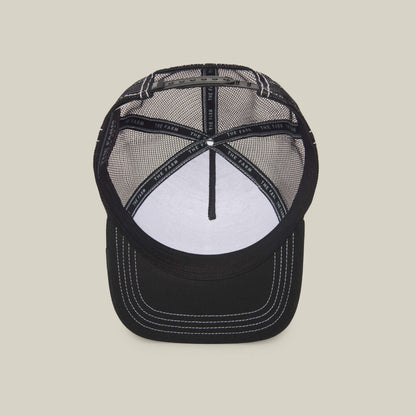 The Queen Bee by The Farm: a black mesh trucker hat with white stitching, inner band featuring THE FARM text, and a white front panel—crafted for those who rule style with confidence.