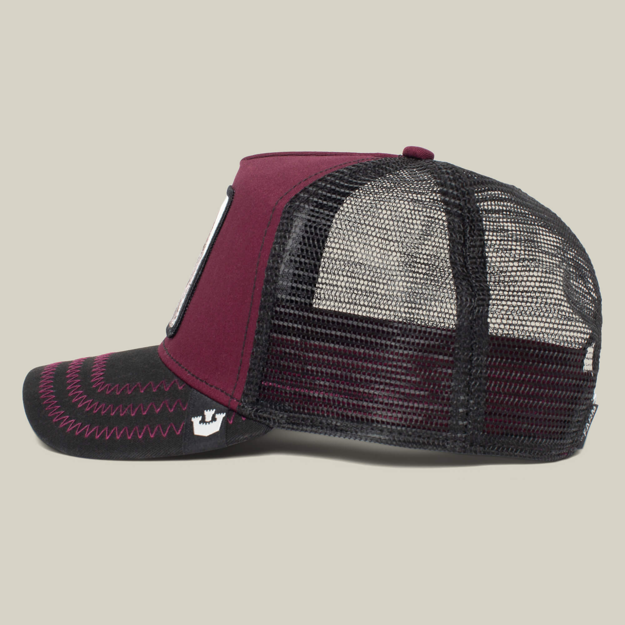 Side view of The Boss by The Farm, a maroon and black trucker hat with mesh back and fabric front featuring visible stitching—a bold standout accessory. Add to cart for instant flair.