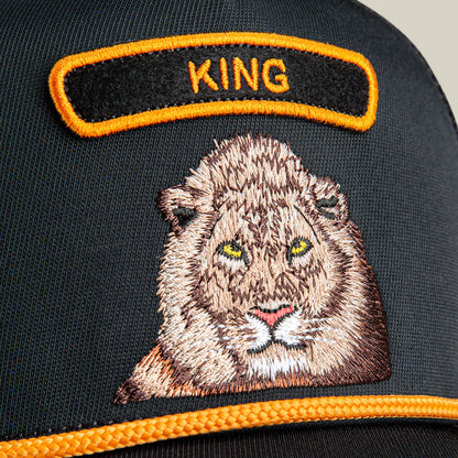 Close-up of The Farm’s GB2 Lion black cap with an embroidered lion face and “KING” in yellow, symbolizing strength and authority.