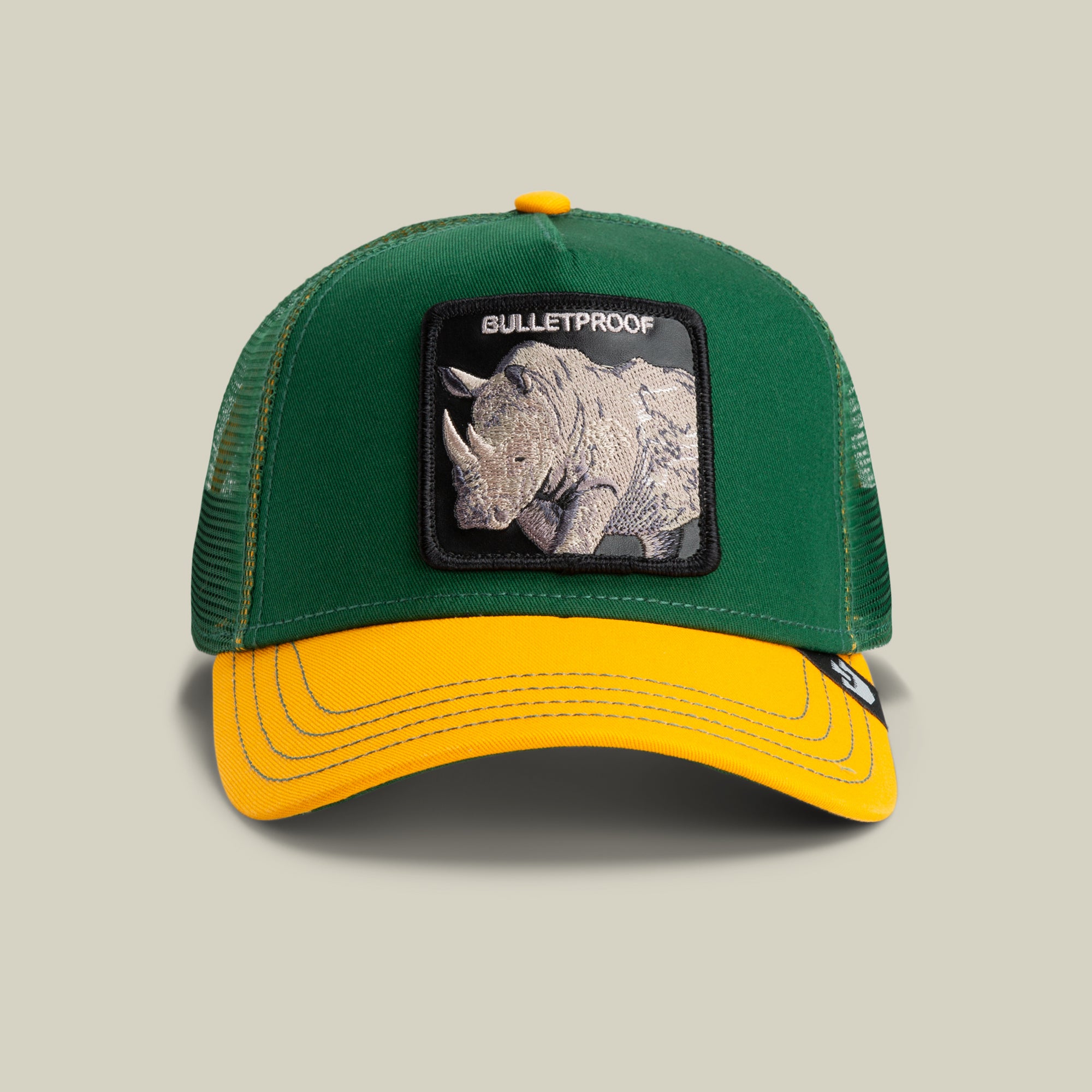 The Farm's "The Bulletproof Rhino" is a green trucker hat with a mesh back, featuring a rhino patch and "BULLETPROOF" on the front. All sales are final.