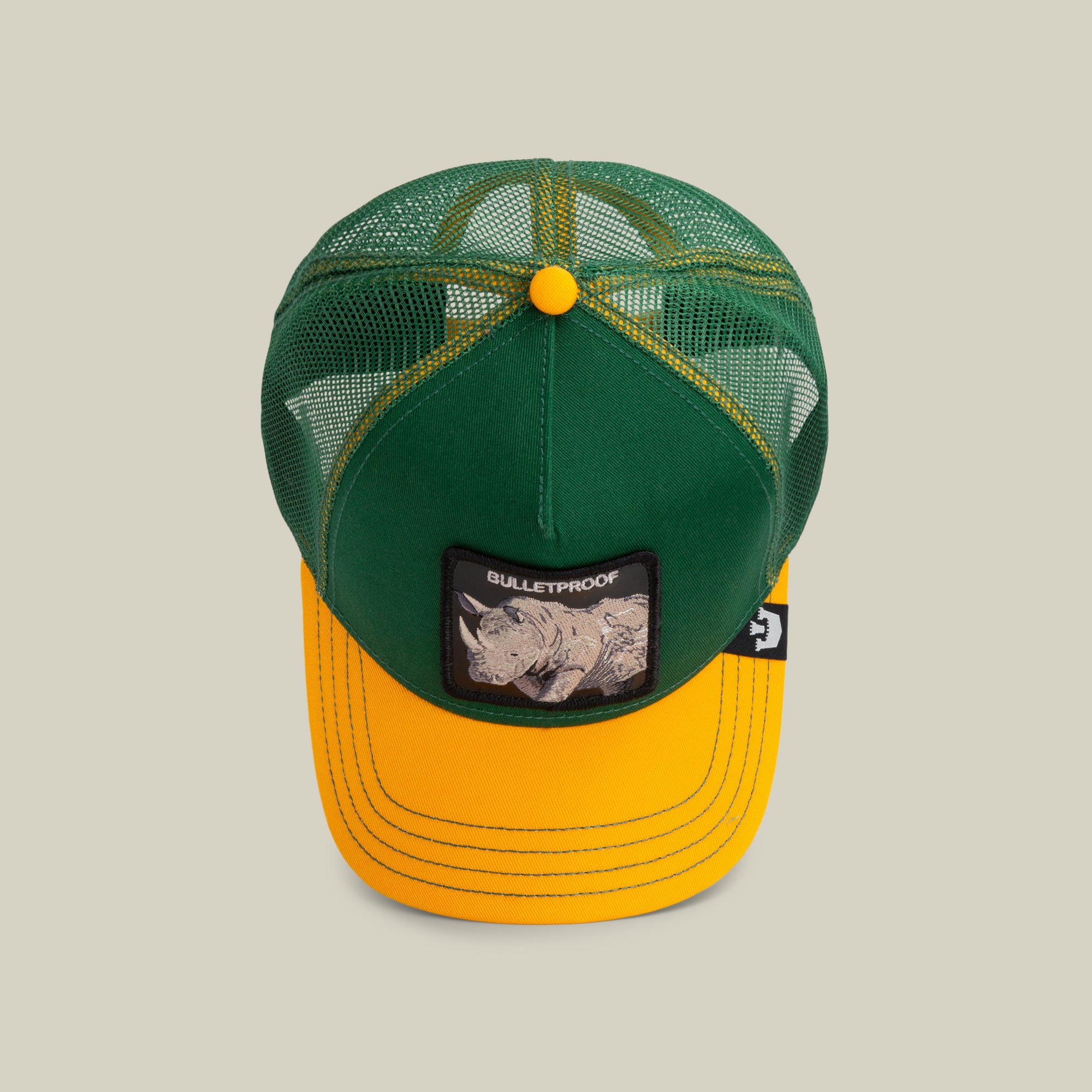 The Farm's "The Bulletproof Rhino" is a green and yellow trucker hat with mesh panels, yellow stitching, and a front patch of a rhinoceros and "BULLETPROOF." All sales are final.