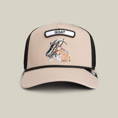 The Farm’s GB2 Goat Trucker Hat in beige and black features a mesh back, an embroidered goat, and a front patch labeled GOAT—a bold badge of honor for champions.
