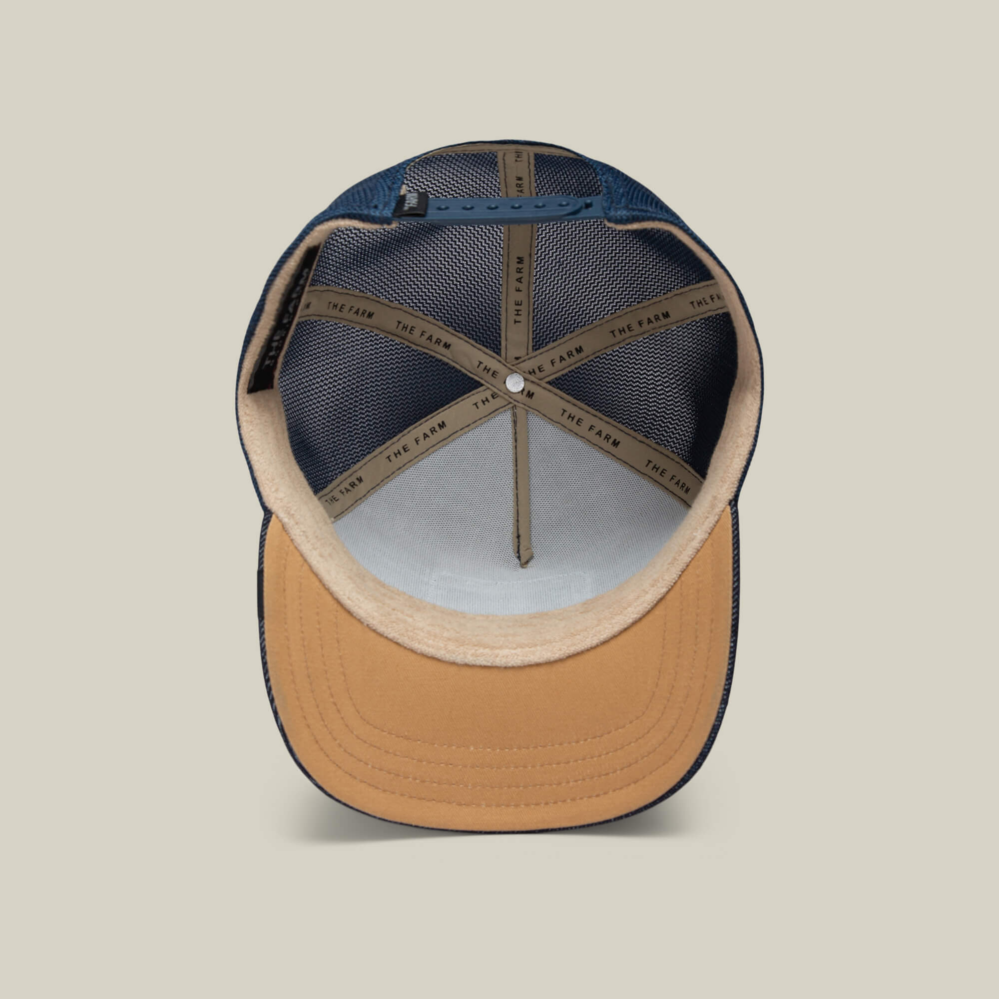 A look inside The Bandit Coyote by The Farm: a two-tone baseball cap with a tan brim, navy panels, and "THE FARM" text on the inner seams—ideal for those with a wild spirit.