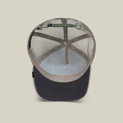 An inside view of The Farm's The Bandit Coyote beige and black trucker hat reveals mesh back panels, an adjustable strap, and THE FARM on the inner sweatband—crafted for those with outlaw energy.