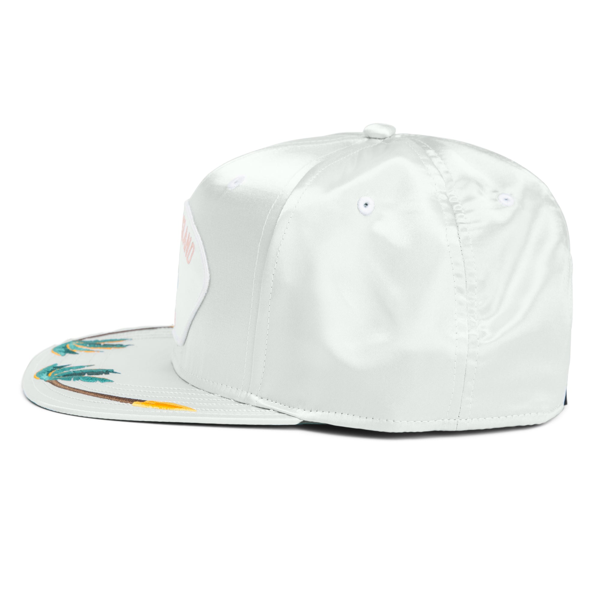 The Goorin Bros. Island Getaway is a white satin snapback hat featuring an embroidered boardwalk motif on the brim and a front patch, inspired by Coney Island, displayed from a side angle.