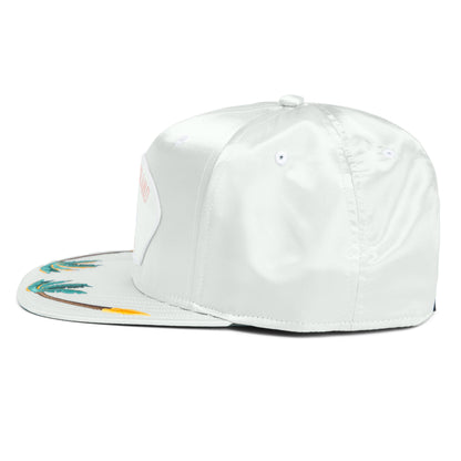 The Goorin Bros. Island Getaway is a white satin snapback hat featuring an embroidered boardwalk motif on the brim and a front patch, inspired by Coney Island, displayed from a side angle.