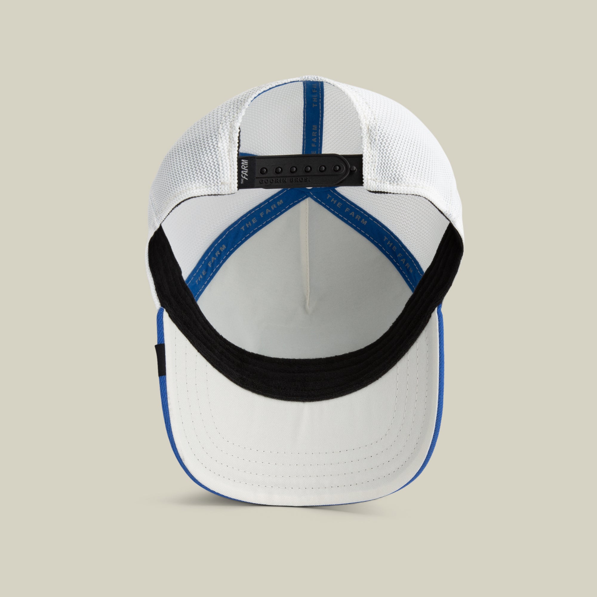 The Farm Lionfish Heat cap in white and blue, shown from above to display the inside, black sweatband, mesh back panels, and adjustable strap. All Sales Final.
