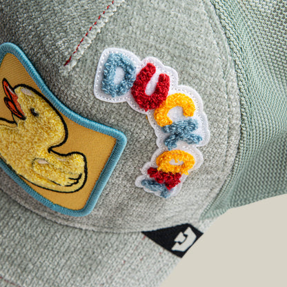 A close-up of the Goorin Bros. Ducking Autocorrect cap—a light gray textured hat with a yellow duck patch and "duck" embroidered in colorful letters, making it a playful and funny addition to any novelty hat collection.