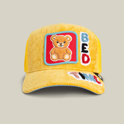 The Duvet All Det hat by Goorin Bros. in BEAM features a teddy bear patch and colorful "BED TIME" embroidery, perfect for adding Bed Time Energy to your style.