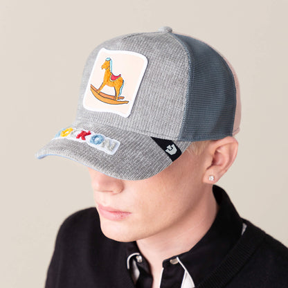 A person sports the Goorin Bros. "Hobby Horse" light gray mesh cap, featuring a rocking horse patch and colorful lettered brim, blending nostalgic charm with modern streetwear against a plain background.