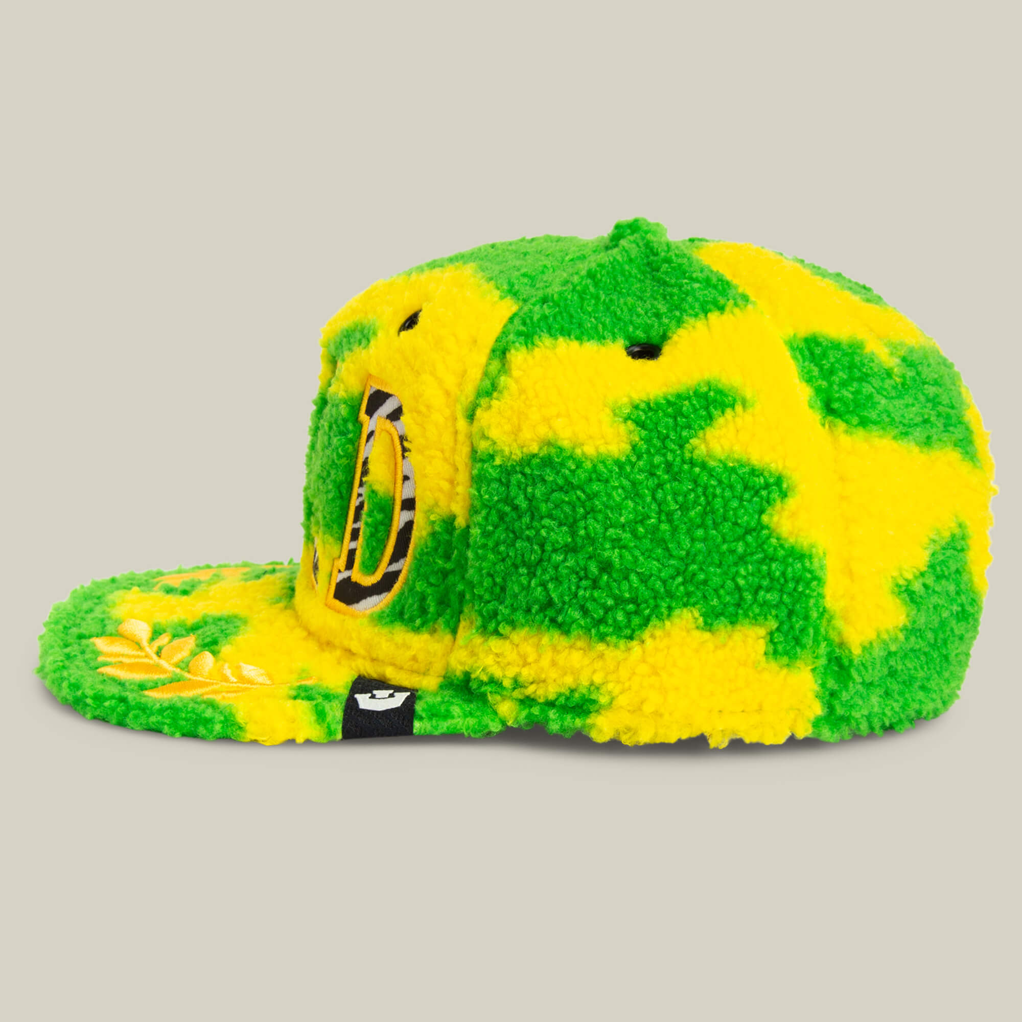 The Loose Cannon by Goorin Bros. is a fuzzy baseball cap with a neon green sherpa camo pattern, featuring a large jungle-style D on the side and a small black tag above the brim.