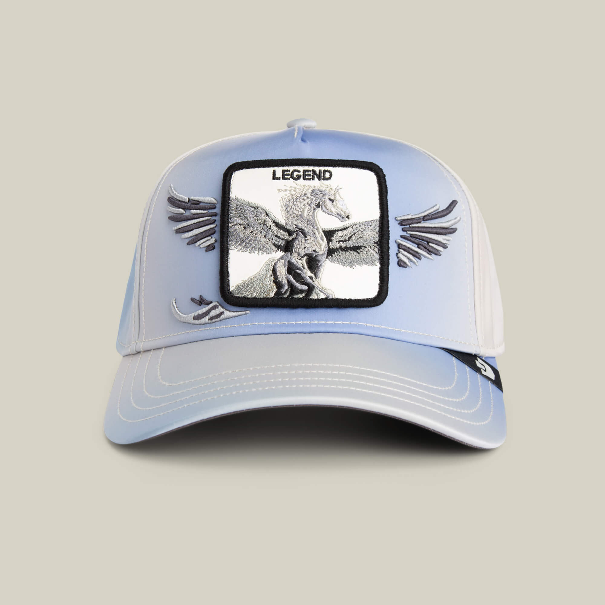 The Flare Up cap by Goorin Bros. features light blue and white panels, contrast stitching, a winged Pegasus "LEGEND" patch, and embroidered wings extending from the patch onto the cap.