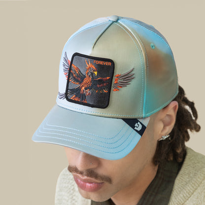 A person wearing the Goorin Bros. "Never Stop Never Stopping" sky-blue crown cap with an embroidered phoenix and FOREVER patch on front, looking downward.