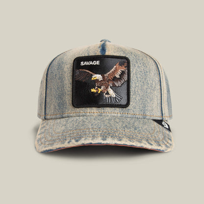 The Goorin Bros. Frequent Flyer is a light denim cap with a front patch showing an embroidered eagle and the word SAVAGE above it.