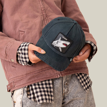 A person holding the Smurf cap by Goorin Bros., its jagged grin patch bringing extra attitude to their style.