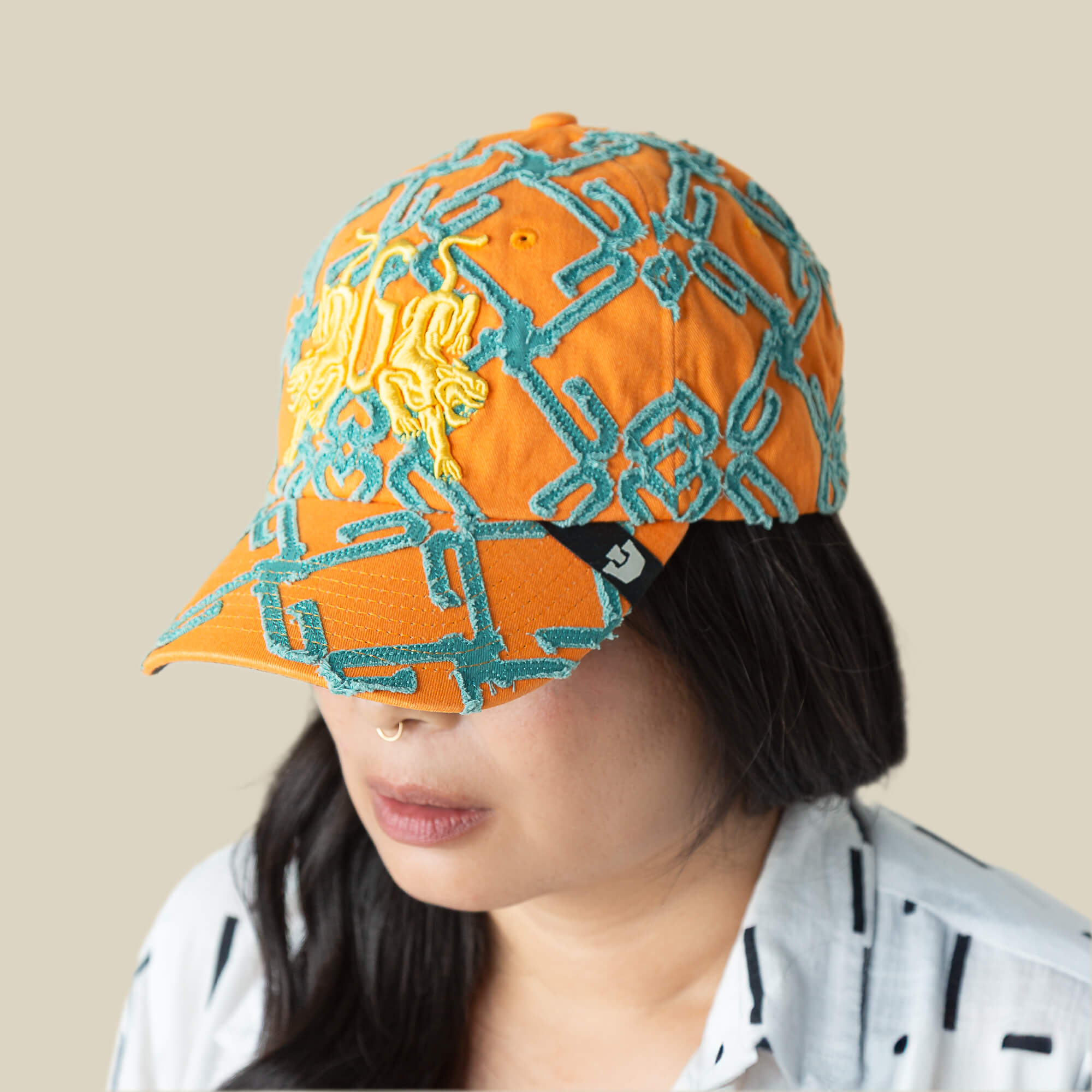 A person with long dark hair wears the Goorin Bros. "Future Baby Daddy" cap with all-over embroidery and a white shirt with black stripes, exuding main character energy against a plain beige background.