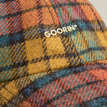 Close-up of the Bespoke Wordmark cap by Goorin Bros., featuring a multicolored plaid wool blend and "GOORIN" in white lettering on the front.