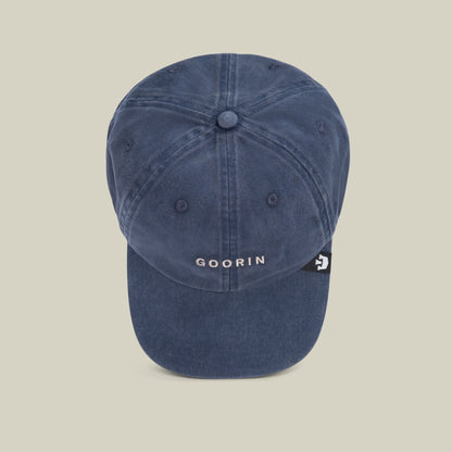 The Papa Cap Italiano by Goorin Bros. is a blue denim baseball cap featuring white "GOORIN" embroidery on the front and a small black tag on the left side, offering a vintage vibe.