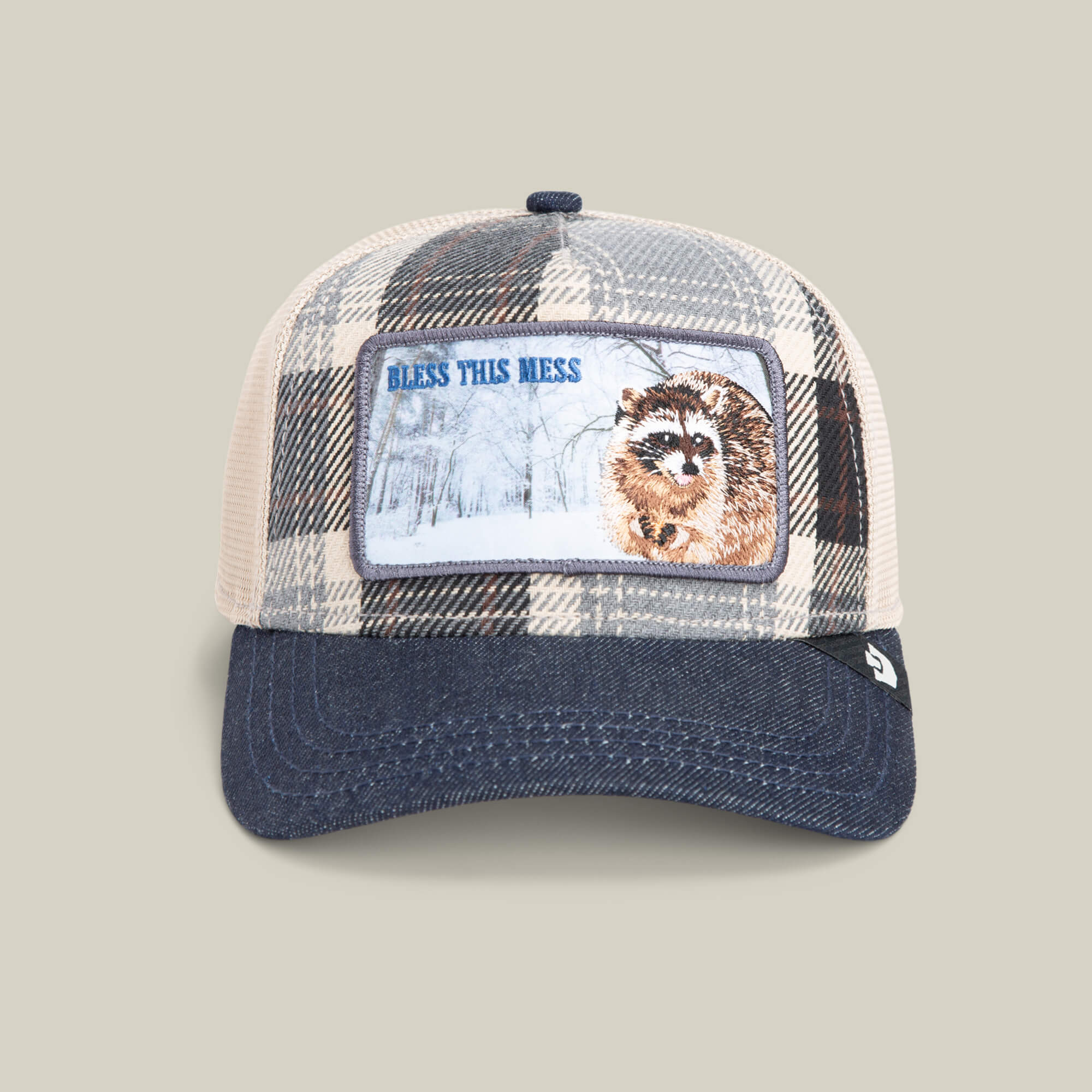The Goorin Bros. Free Spirited hat in PLAID is a mesh trucker style with a denim brim, featuring a raccoon patch, snow-covered trees, and the text "BLESS THIS MESS.