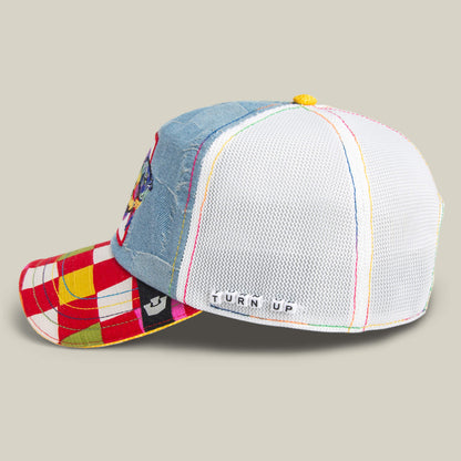 The Goorin Bros. Drum and Bass hat features a denim front, white mesh back, red and yellow plaid brim, and a TURN UP label—this colorful patchwork is perfect for bass lovers ready to rave.