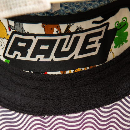 A close-up of the Goorin Bros. Acid House hat, featuring a patterned brim and RAVE label inside, surrounded by cartoon animals like a green frog and brown bear, captures playful Acid House vibes perfect for any laser dome party.