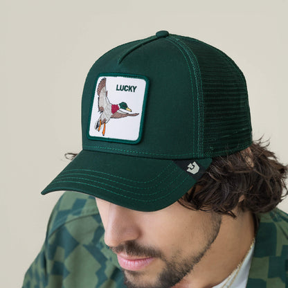 A man wears The Lucky Duck mesh trucker hat by Goorin Bros., featuring a flying duck patch and the word LUCKY on the front—a stylish charm for every adventure.