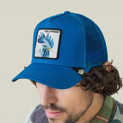 A man wearing the Goorin Bros. Hollywood Rooster cap, a blue mesh baseball hat with a rooster patch—ideal for strolling the Hills or turning heads on the red carpet.