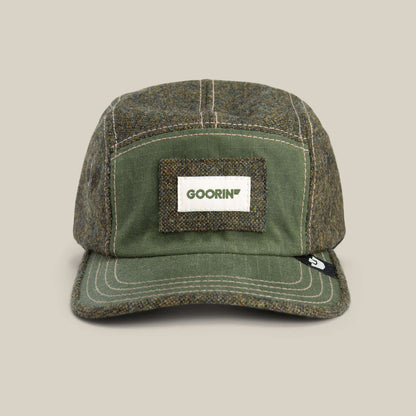 The Goorin Bros. Billed Demand hat in SHADE is a five-panel field cap featuring a rectangular front patch with green GOORIN text.