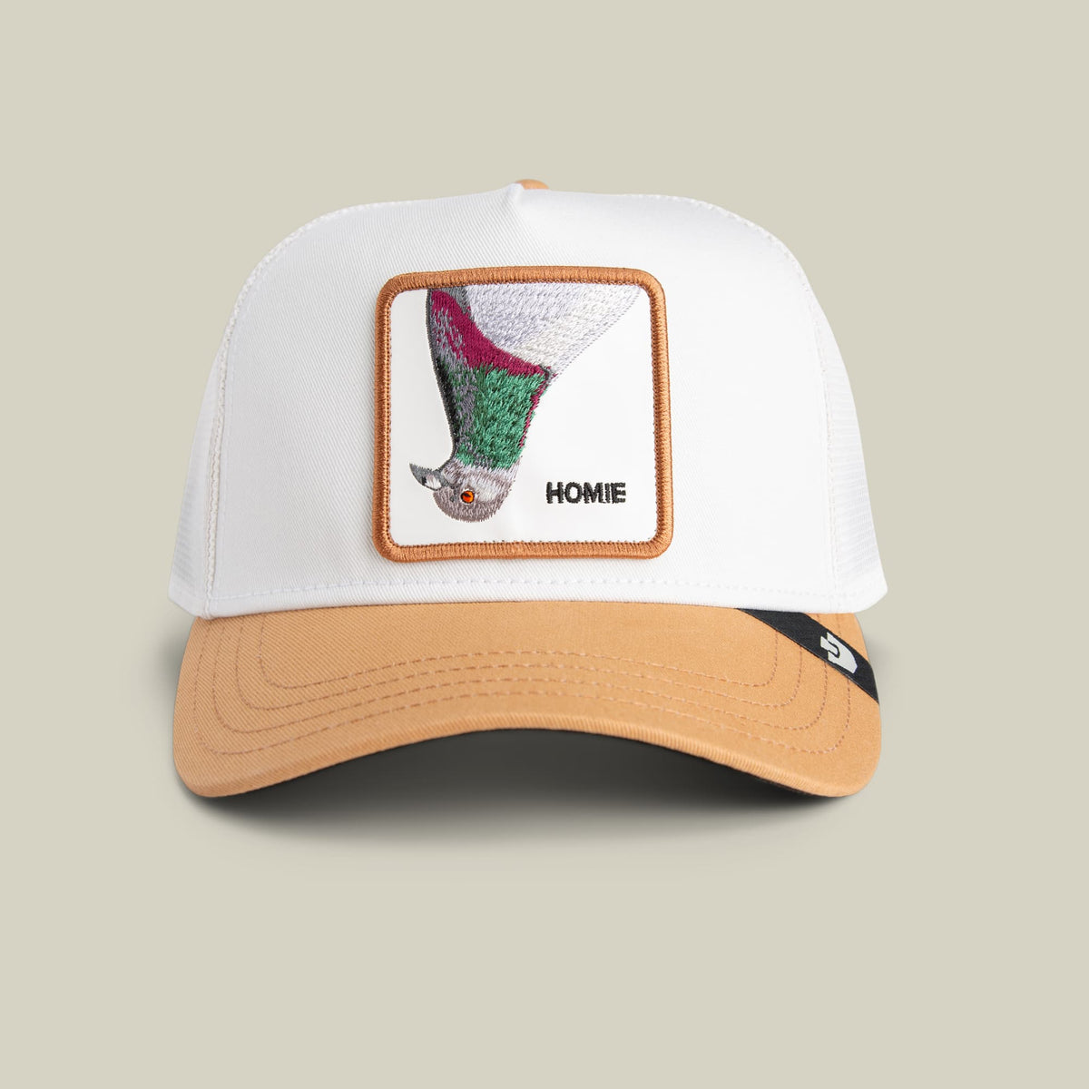 The Goorin Bros. Noegip trucker hat features a white front panel and tan canvas bill with a colorful embroidered patch depicting an upside-down face and the word Homie, displayed against a neutral studio background.