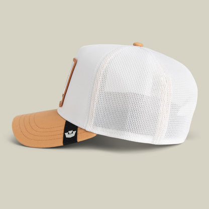 The Goorin Bros. Noegip trucker hat features a white mesh back panel and tan cotton front with an orange bill, displayed on a neutral background with a small branded patch visible on the snapback closure.