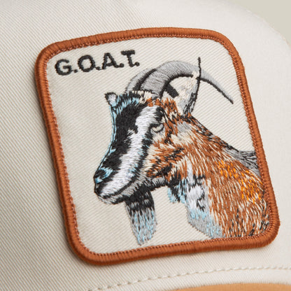 Close-up of The G.O.A.T by Goorin Bros.—a beige hat in neutral tones, featuring a bold patch with an embroidered goat’s head and the text "G.O.A.T.