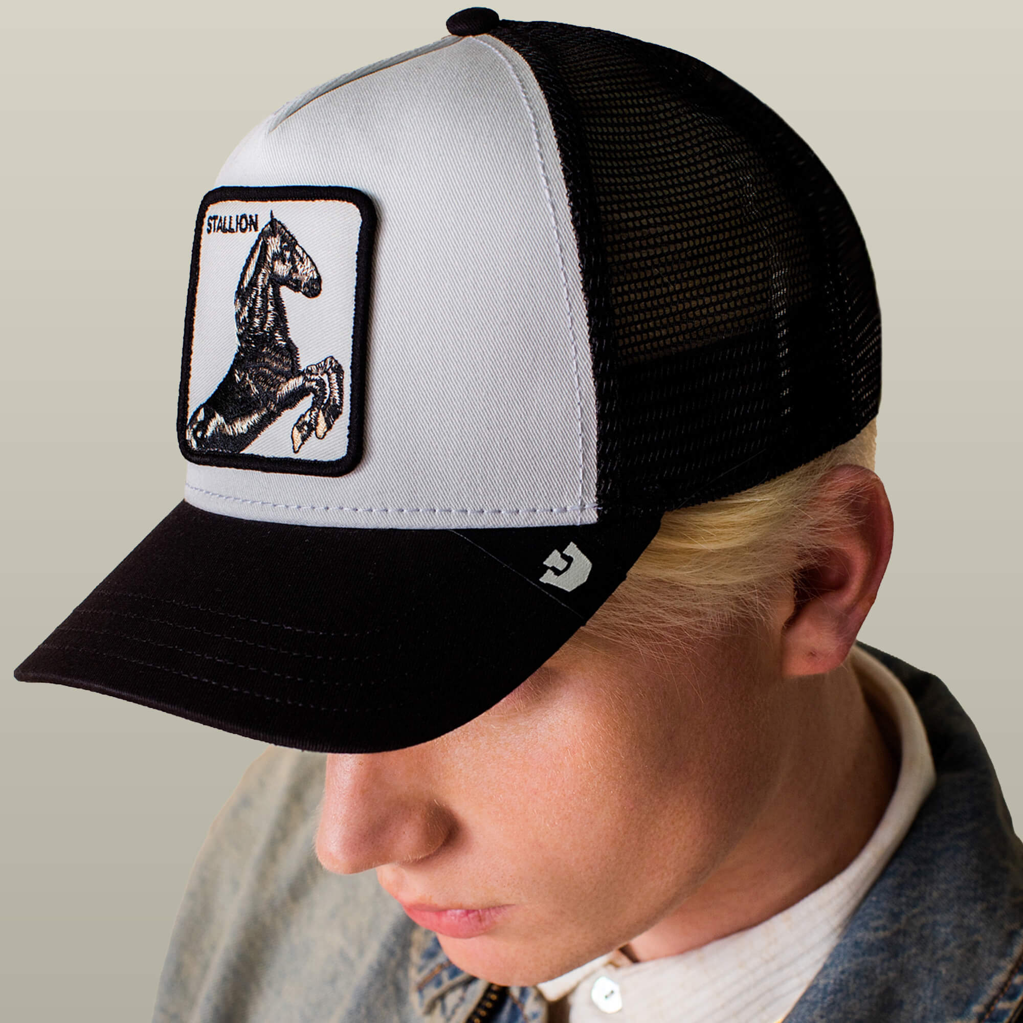 A person wearing the Goorin Bros. Stallion Trucker, a black and white mesh back hat with a stallion patch, viewed from above at a slight angle.