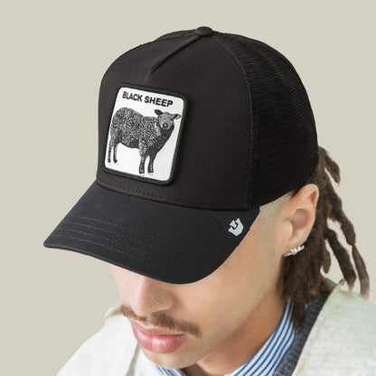 Wearing The Black Sheep cap by Goorin Bros., featuring a black sheep patch and "BLACK SHEEP" text, this person looks downward—capturing the spirit of standing out from the crowd.