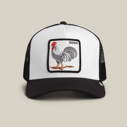 The Goorin Bros. "The Rooster" trucker hat in DUST / VOID features a rectangular rooster patch with the word COCK embroidered in the top right corner.