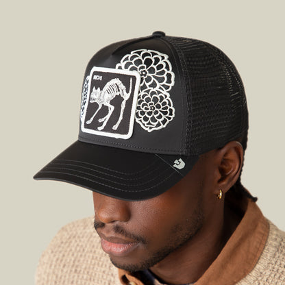 A person wears the Goorin Bros. Dia De Michi black mesh baseball cap, featuring oversized embroidered florals and a patch with a cat skeleton.
