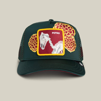 The Goorin Bros. "Dia De Potro" trucker hat in GUARD features yellow and red floral embroidery, bold stitching, and a front patch with sharp lines, a white horse skeleton, and "POTRO.