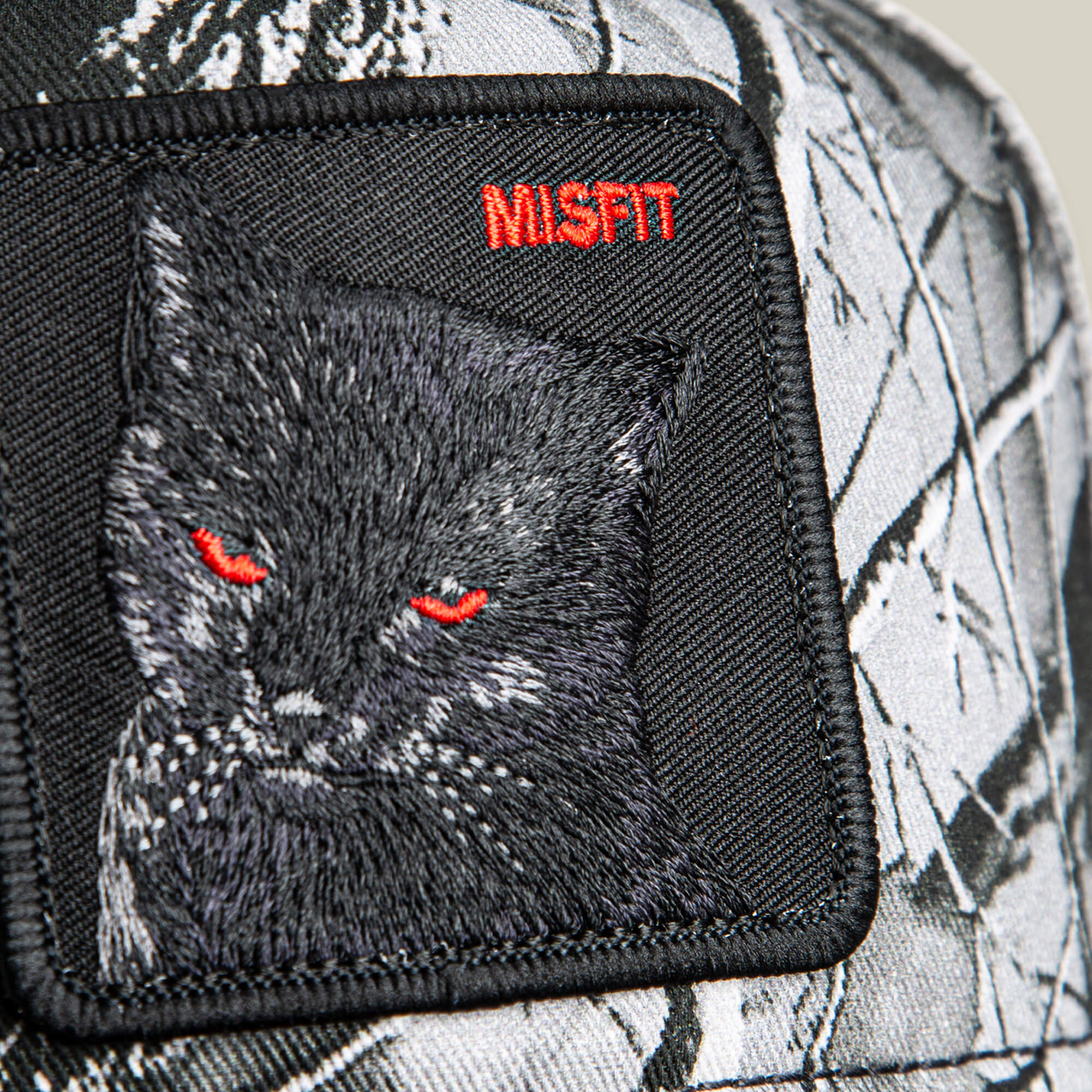 Close-up of the Goorin Bros. Misfit Camo Low Pro Fit hat, featuring a black cat patch with red eyes and "MISFIT" stitched in red.