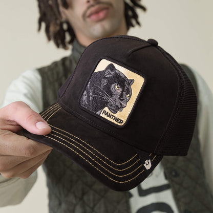 A person with dreadlocks holds the Goorin Bros. Golden Panther hat, featuring a microsuede crown and a front patch with a Golden Panther and the word "PANTHER".