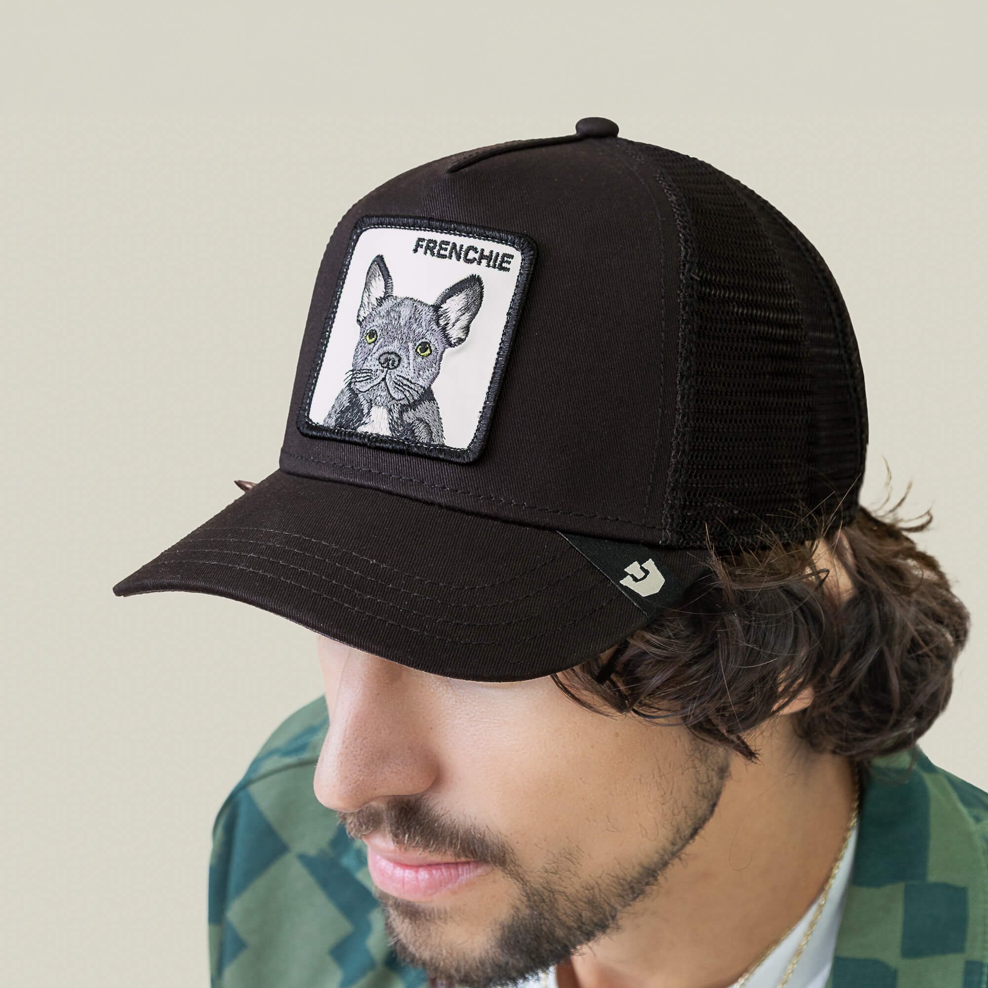 A man wearing Goorin Bros.' The Frenchie Dog black mesh trucker hat with a patch featuring a French Bulldog illustration and "FRENCHIE" on the front.