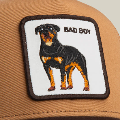 The Bad Boy by Goorin Bros. is a stylish brown cap with a square patch featuring an embroidered Rottweiler and BAD BOY text on a white background.