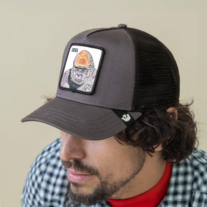 A man wearing the Goorin Bros. Boss Trucker hat, featuring a dark mesh design and a gorilla patch with "BOSS" on the front, looking downward.