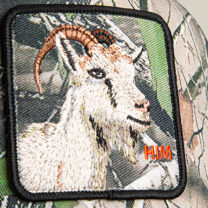 The Goorin Bros. Camouflage Goat hat patch features an embroidered goat in brown, black, and white, with "HIM" stitched in orange on the lower right corner.